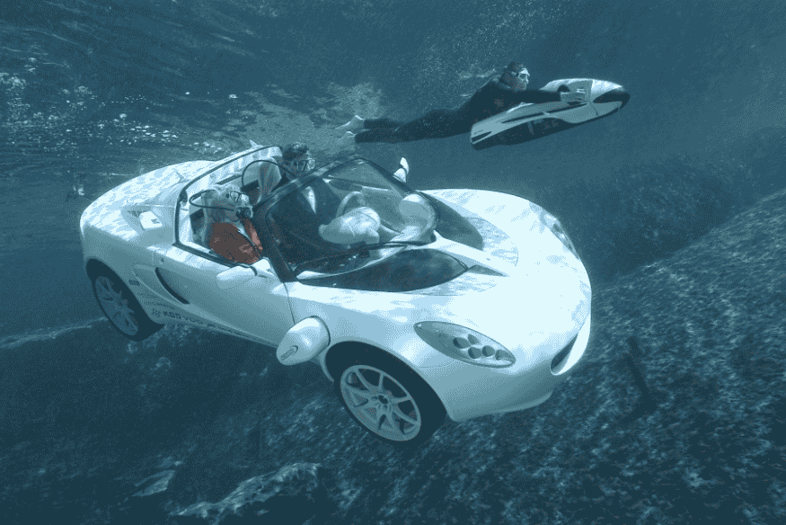 Rinspeed sQuba submerso com ocupantes e mergulhador ao lado, demonstrando a capacidade subaquática do carro-conceito suíço