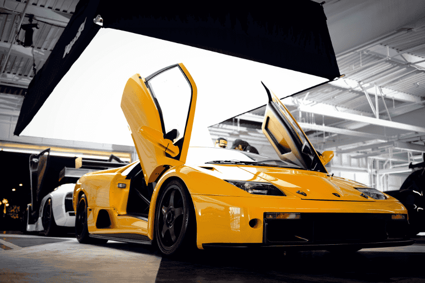 Lamborghini Diablo amarela com portas abertas para cima, exposta em evento automotivo interno.
