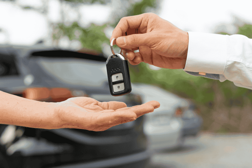 Pessoa entregando uma chave de carro para outra, simbolizando a entrega de um veículo por assinatura.