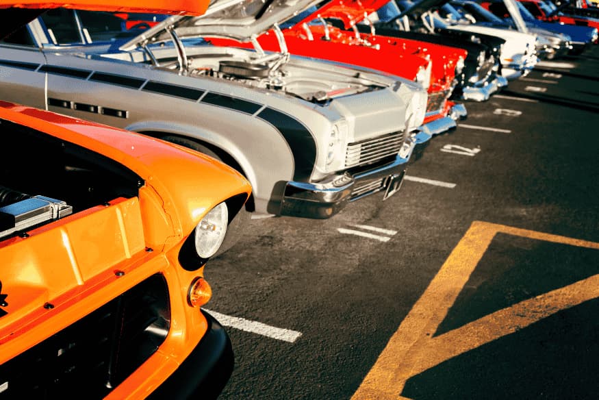 Fileira de carros clássicos com os capôs abertos em exposição