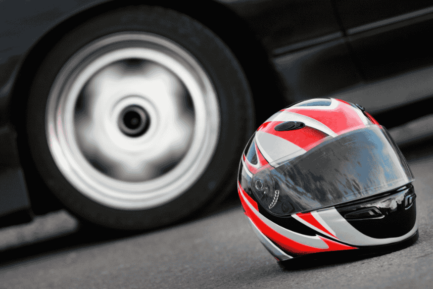 Capacete de corrida com design esportivo ao lado de carro de competição.