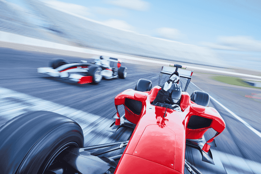 Carros de Fórmula 1 disputando uma corrida em alta velocidade em autódromo.