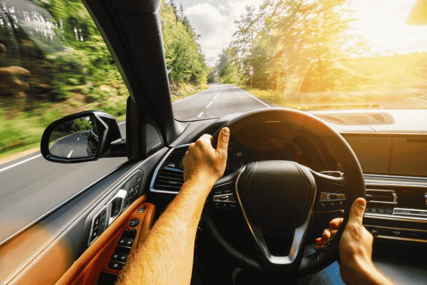 Condutor dirigindo um carro moderno com volante multifuncional.