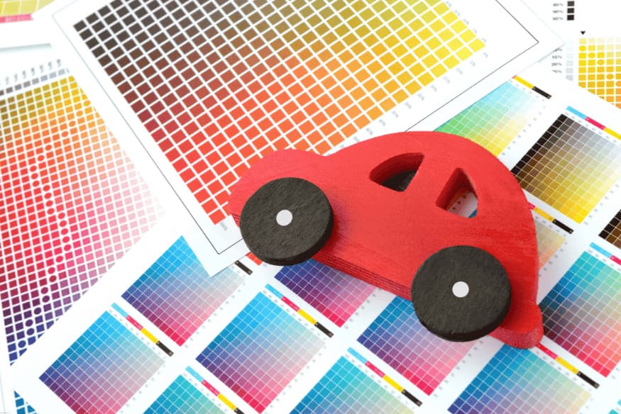 Miniatura de carro vermelho sobre amostras de cores automotivas impressas