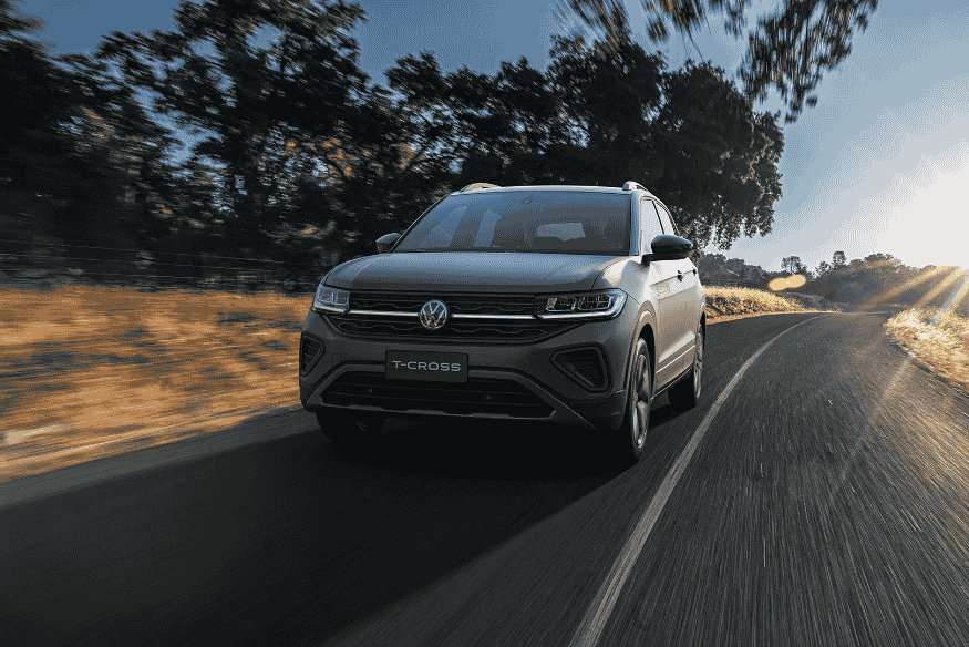 Volkswagen T-Cross em estrada asfaltada, com pôr do sol ao fundo.