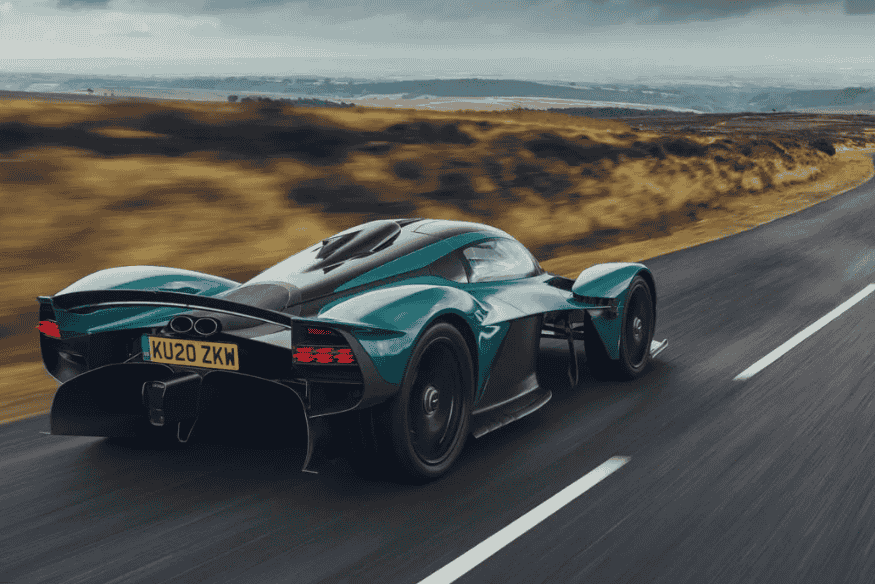 Aston Martin Valkyrie em alta velocidade em estrada aberta, com design aerodinâmico e estilo futurista.
