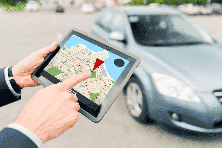 Homem utilizando tablet com mapa e marcador GPS para localizar um carro estacionado ao fundo