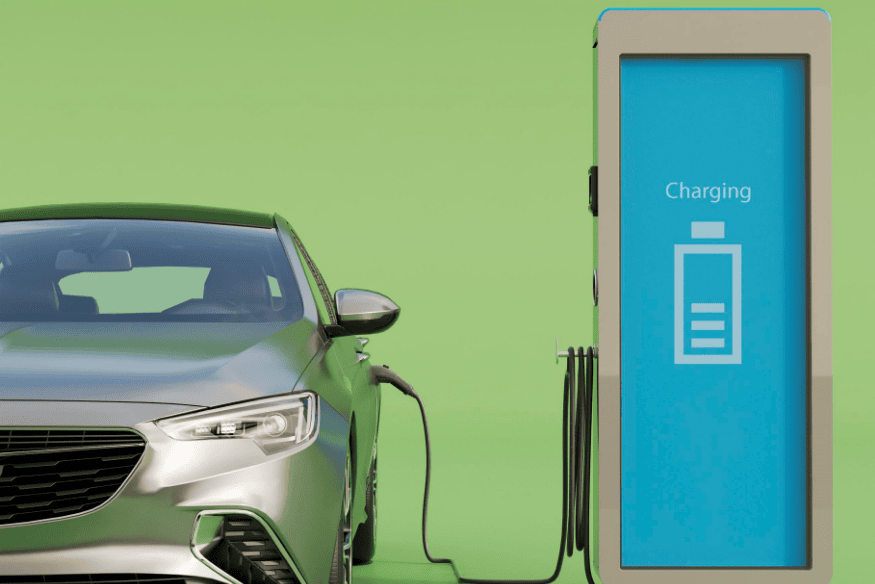 Carro elétrico prateado conectado a uma estação de recarga com tela azul exibindo "Charging"