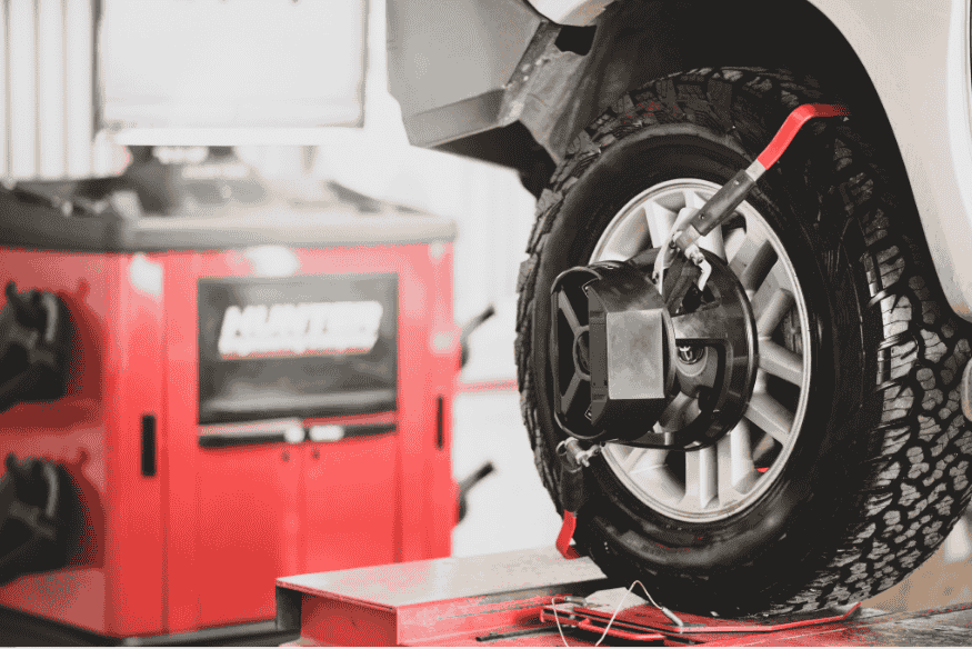 Máquina realizando alinhamento de rodas em pneu off-road de veículo.